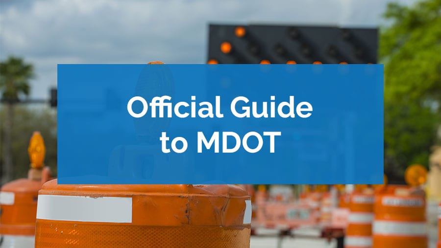 Blue sign reading 'Official Guide to MDOT' with traffic signal in background.